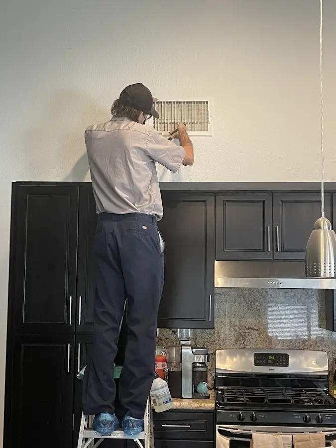 Technician inspecting an air vent during HVAC service in Greeneville